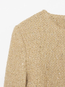 Détail de la veste en tweed doré champagne avec paillettes et texture du col rond