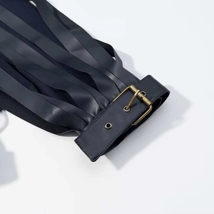Detail of a black faux leather tiered fringe jacket with a vintage gold metal buckle belt