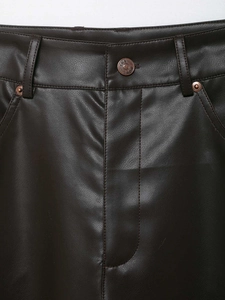 Dettaglio dei pantaloni in pelle marrone scuro con cuciture in vita e bottone in metallo