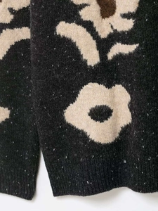 Close-up detail of floral jacquard knit texture with fuzzy soft fabric in black and beige