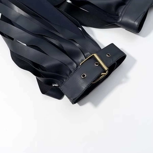 Detailed close-up of punk style black leather fringe tassels with gold buckle fasteners