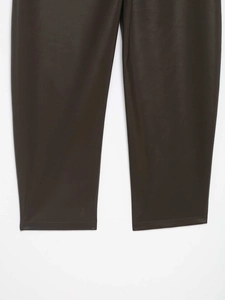 Dettaglio ravvicinato dei pantaloni in ecopelle marrone scuro con cuciture sull'orlo