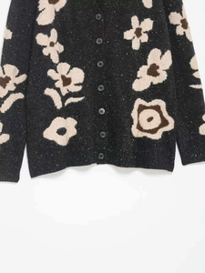 Close-up of floral jacquard knit texture with vintage buttons and ribbed cuffs
