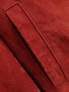 Macro detail of the pocket stitching and texture on a red faux suede jacket