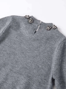 Close-up of grey knit top back neckline featuring crystal beadwork and button closure