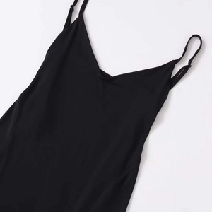 Minimalist black spaghetti strap dress with an asymmetrical hemline shown in a flat lay view