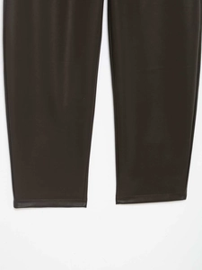 Dettaglio ravvicinato dei pantaloni in ecopelle marrone scuro con cuciture e trama del tessuto