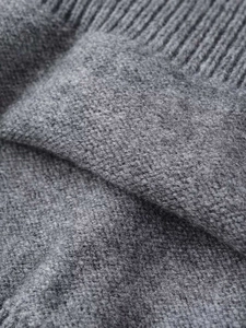 Close-up of dark grey knitted sweater fabric showing soft wool texture and ribbed cuffs