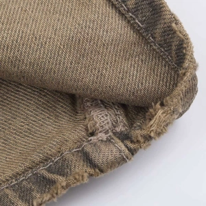 Detailed macro view of vintage brown denim trousers with frayed hem and twill fabric texture
