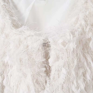 Détail de la veste en plumes blanches avec paillettes et crochet métallique invisible