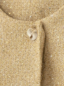 Détail du tissu tweed aux fils dorés avec paillettes et bouton métallique en spirale