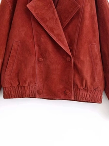 Detail of rust red suede jacket showing double-breasted buttons and elastic hem