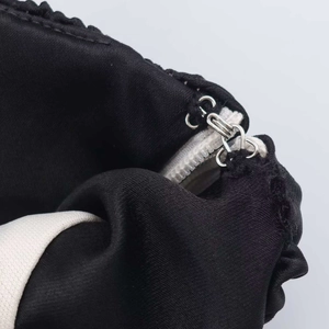 Dettaglio dell'abito a fascia in raso nero con gancio metallico e cerniera lampo invisibile