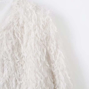Détail de la texture à franges blanches douces sur ce gilet en maille à manches longues