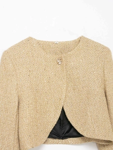 Détail de la veste en tweed doré avec fils métalliques, paillettes et bouton doré