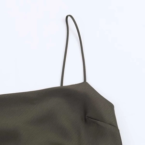 Detailed macro view of olive green satin dress featuring fine straps and smooth texture