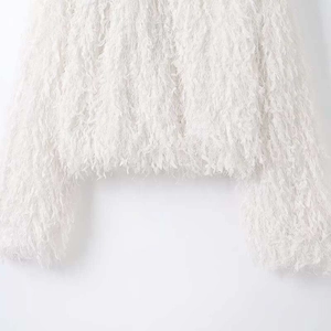 Gros plan d'une veste blanche à manches longues avec détails de franges en fausse fourrure