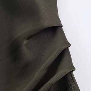 Detailed macro view of olive green satin fabric with delicate lace trim and subtle textures
