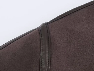 Dettaglio macro in maglia scura con bordino in pelle marrone e cuciture di precisione