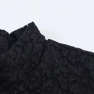 Close-up of black floral lace stitching and delicate hollow mesh texture on dress fabric