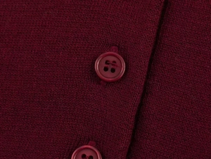 Close-up of wine red knitted sweater fabric featuring a matching four-hole button detail