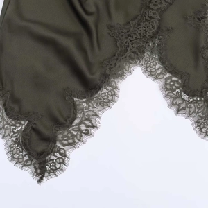 Detail of dark olive satin dress showing floral lace trim and delicate eyelash fringe