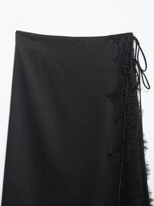 Detail view of black satin skirt featuring delicate eyelash lace trim and side lacing