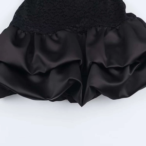 Detailed close-up showing black lace patchwork and pleated satin fabric on the dress