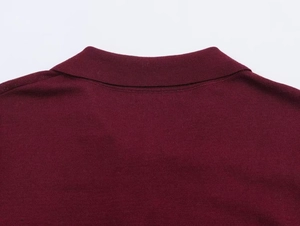 Close-up of the fine knit texture and collar detail on a burgundy long-sleeve polo shirt