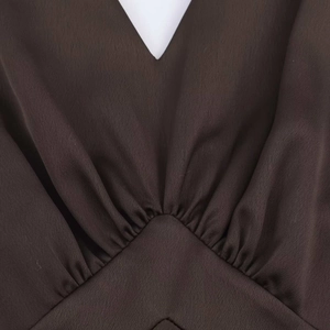 Dettaglio dell'abito midi in raso color cioccolato con scollo a V e pieghe fitte