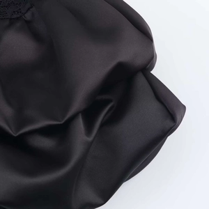 Detail of black satin dress featuring delicate lace trim and smooth silky texture