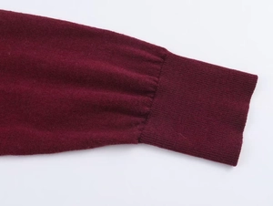 Detailed close-up of ribbed cuffs on a burgundy knitted sweater for women