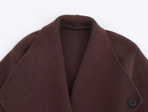 Détail de cardigan en tricot marron foncé avec col à revers et bouton noir