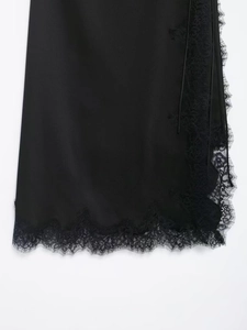 Detailed view of elegant black satin skirt hem featuring delicate floral eyelash lace trim