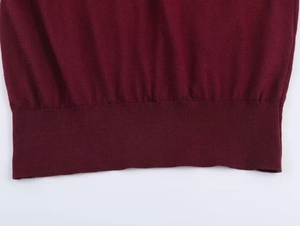 Close-up of a burgundy knit sweater showing high-quality ribbed hem and fabric detail