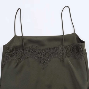 Detail of dark green satin dress featuring delicate lace trim and thin shoulder straps