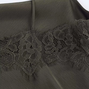 Detail of eyelash lace trim on olive green satin dress neckline with thin strap