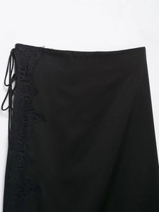 Detail of black satin skirt featuring delicate eyelash lace trim and side tie design
