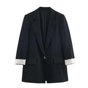 Detail of black blazer featuring a gold button and striped lining on cuffed sleeves