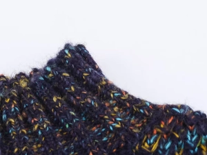 Detailed macro view of chunky rib-knit fabric with colorful specks in dark blue wool