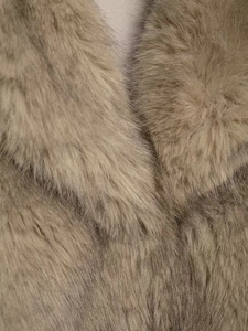 Close-up of premium thick faux fur texture on a warm camel winter coat collar