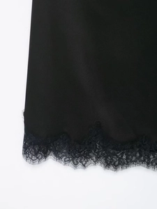 Close-up of black satin skirt hem with delicate eyelash lace trim and fine craftsmanship