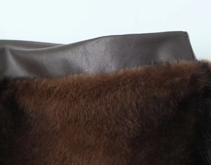 Detailed close-up of dark brown faux fur and litchi-grain leather texture on the skirt