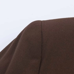 Detailed macro view of high-quality brown woven fabric and stitching on blazer shoulder