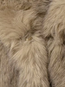 Close-up of warm faux fur texture with a hidden metal hook closure in tan color