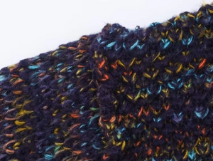 Detailed macro view of heavy chunky knit fabric with mixed purple and orange yarns