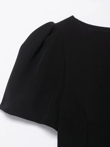 Detail of elegant black dress showing puff sleeve design and premium pleated fabric texture