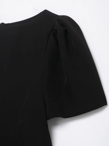 Detailed close-up of the puff sleeve design and pleated shoulder texture on the black dress