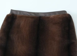 Detailed macro view of dark brown faux fur texture and smooth faux leather waistband