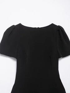 Close-up of black bodycon dress featuring a bateau neck and short puff sleeves with ruffles